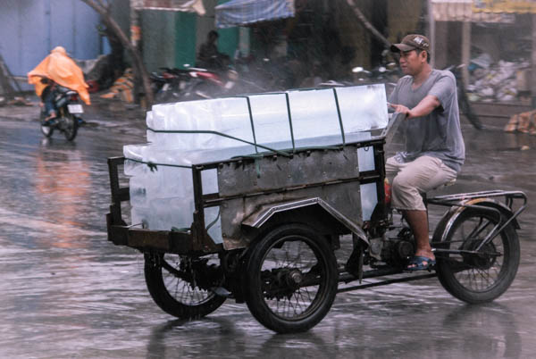 Mann transportiert sehr große Eisblöcke auf einem Lastenmoped