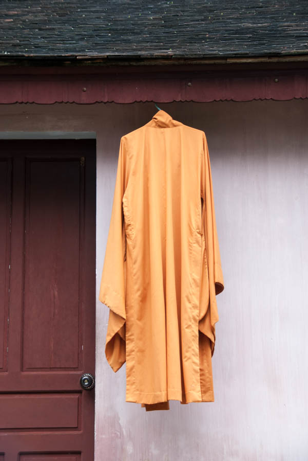 Orange Mönchskutte eines Priesters hängt unter einem Dachvorsprung