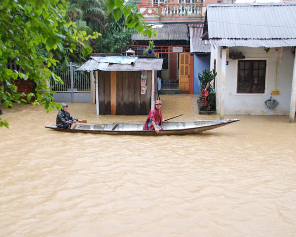 Kanu mit zwei Personen und Regenkleidung, überflutete Strasse