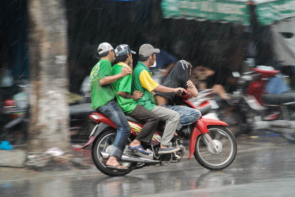 Ein Moped fährt 4 Jugendliche durch den Regen